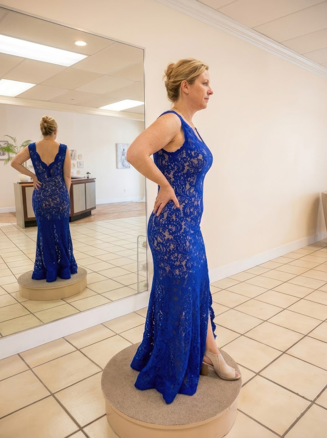 Client checking the fit of a royal blue lace mermaid gown in the studio mirror